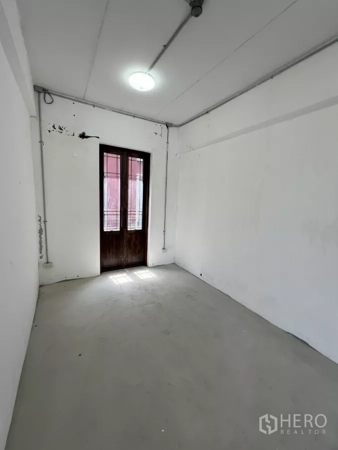 Retail Space for rent in Khlong Toei, Bangkok - Narrow white room with a wooden door and natural light.