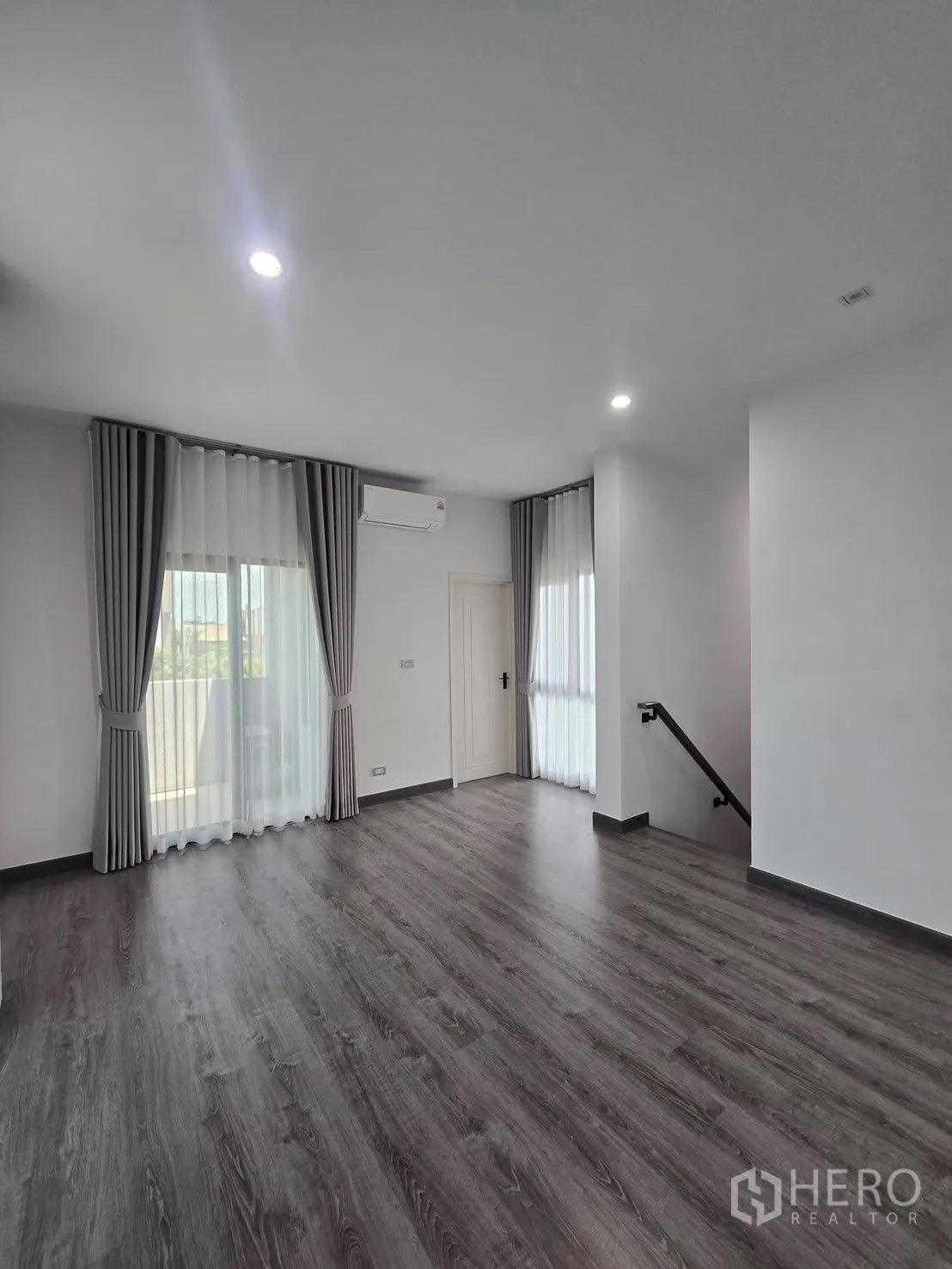 บ้านแฝด for rent in Suan Luang, Bangkok - ห้องชั้นบนกว้าง พื้นลายไม้ ผ้าม่าน และโถงบันไดเชื่อมต่อ.