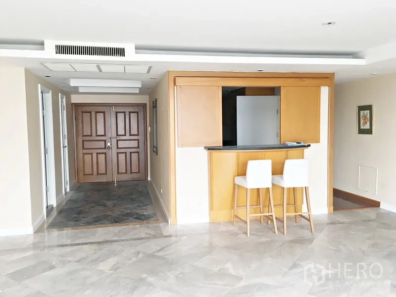 公寓 出租在Pathum Wan, Bangkok - 明亮的玄关，双扇木门、石材地面与内置吧台配两把高脚椅。