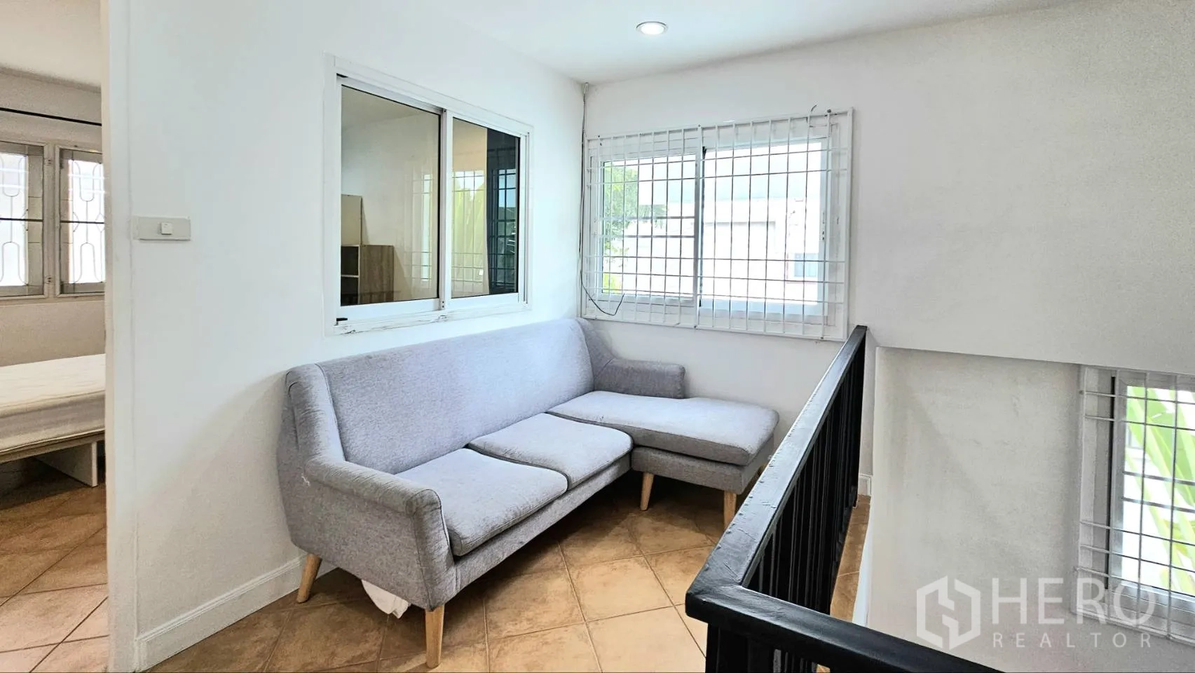 独栋房屋 for rent in Saphan Sung, Bangkok - 二楼休闲区，灰色转角沙发与采光窗，窗上有防护栏。