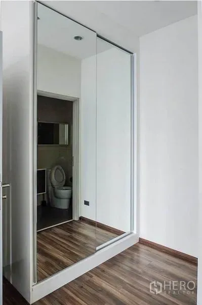 Condominium for rent in Khlong Toei, Bangkok - Hallway with mirrored sliding wardrobe and a view into the modern bathroom.