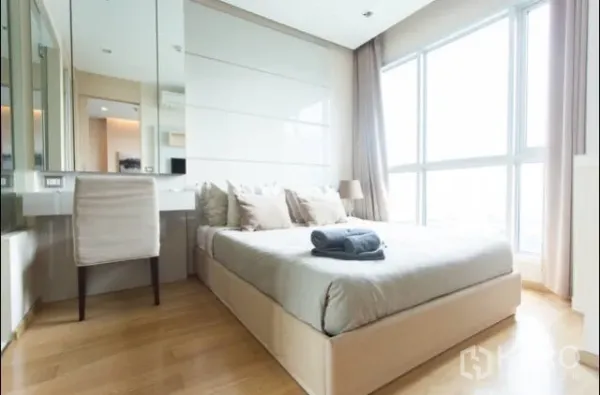 公寓 出租在Ratchathewi, Bangkok - 明亮卧室，落地窗与中性色调，配内置梳妆台。
