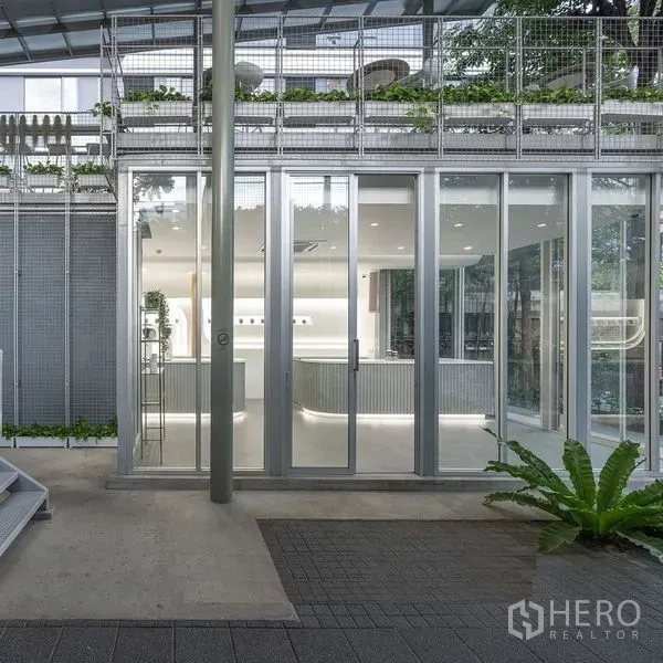 Retail Space for rent in Khlong Toei, Bangkok - Street-level exterior with sliding glass doors, metal facade and greenery at a contemporary retail space.