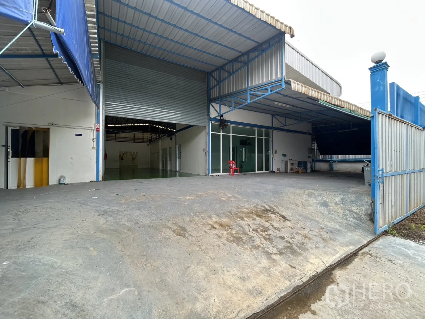Factory for rent or sale in Bang Yai, Nonthaburi - Factory frontage with wide roller shutter, ramped driveway, gate, and covered bay.