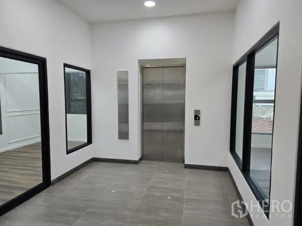 Home Office for rent in Chatuchak, Bangkok - Interior lobby featuring a stainless-steel elevator and glass-walled rooms.