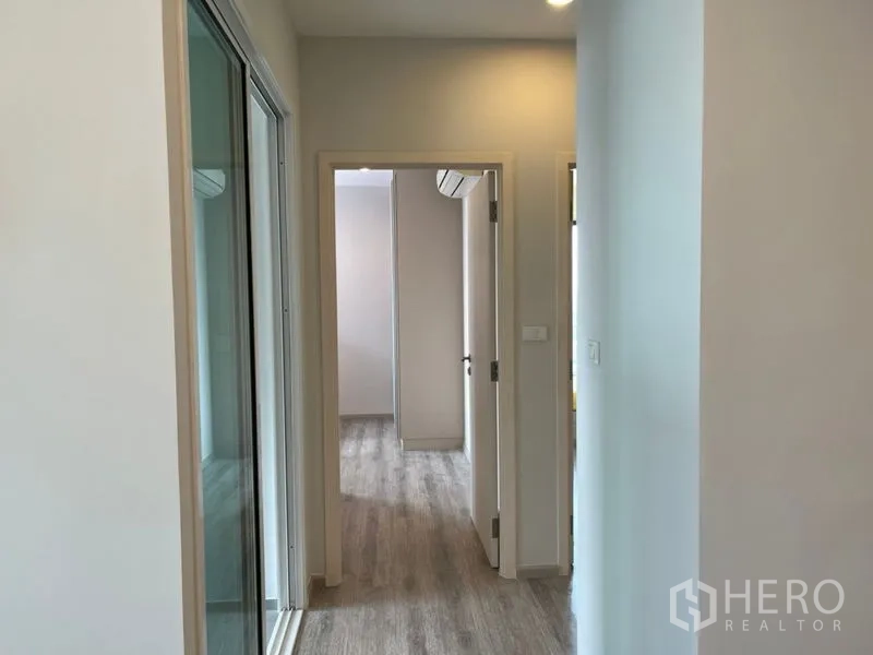 Condominium for sale in Phaya Thai, Bangkok - Hallway with light wood floors leading to bedrooms in the condominium.