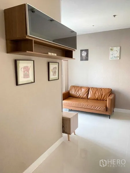 Condominium for rent in Phra Khanong, Bangkok - Built-in shelving and artwork above a leather sofa in the living room.