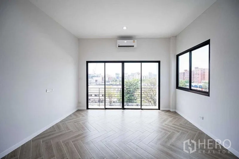 带办公室的家 出租在Suan Luang, Bangkok - 转角房间，人字拼木地板，推拉门连通阳台，可见城市景观。