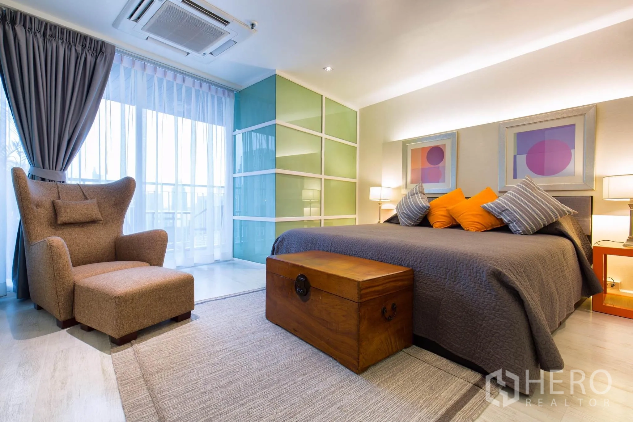 คอนโด ให้เช่าในPathum Wan, Bangkok - ห้องนอนมาสเตอร์พร้อมเตียงคิงส์ หมอนตกแต่ง เก้าอี้เอนพร้อมสเต็ป ตู้เสื้อผ้าบานเลื่อนกระจก และประตูออกสู่ระเบียง