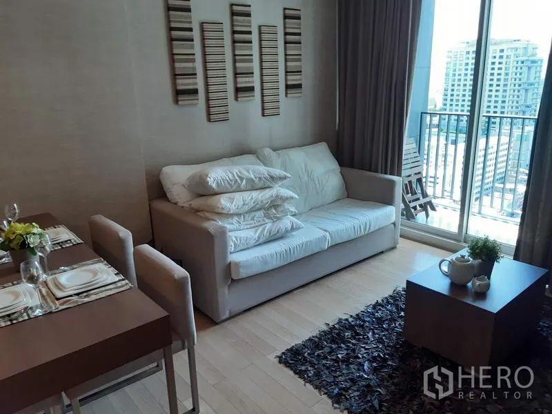 Condominium for rent in Khlong Toei, Bangkok - Bright living area with sofa, dining set and a balcony overlooking Bangkok city views.
