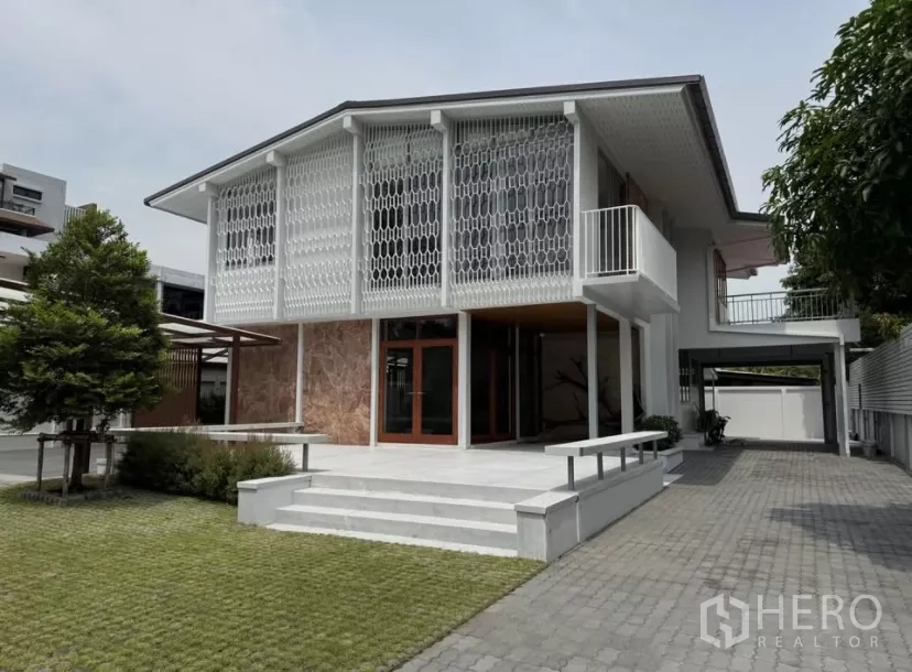 独立式住宅 出租在Watthana, Bangkok - 经过翻新的中世纪风格独栋住宅正立面，镂空立面、草坪与铺装车道。