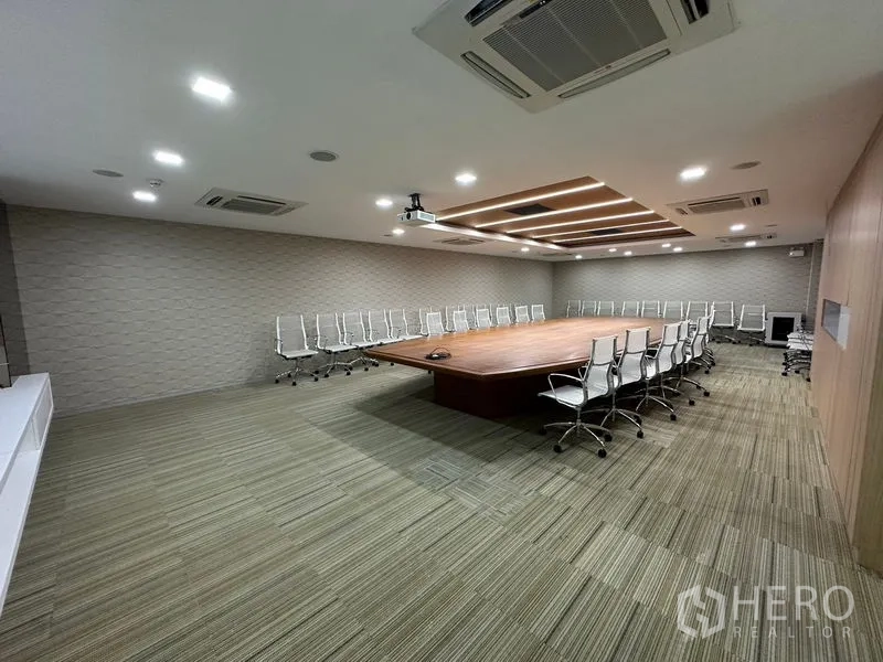 สำนักงาน ให้เช่า - บอร์ดรูมขนาดใหญ่ โต๊ะไม้ตรงกลาง เก้าอี้ขาว และเครื่องโปรเจ็กเตอร์