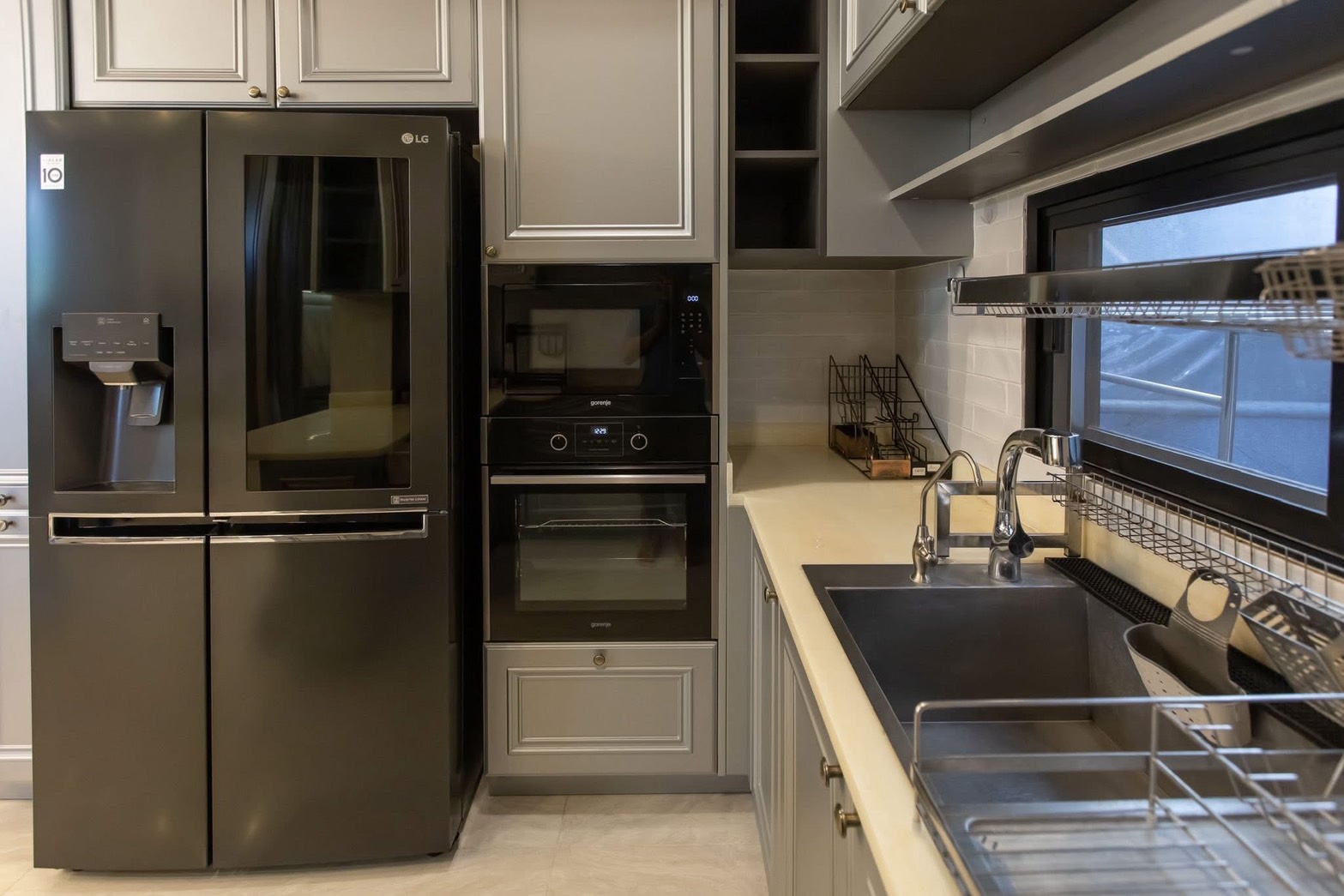 Detached House for rent in Lat Phrao, Bangkok - Modern grey kitchen featuring a black LG French-door fridge, built-in oven, and stainless sink.