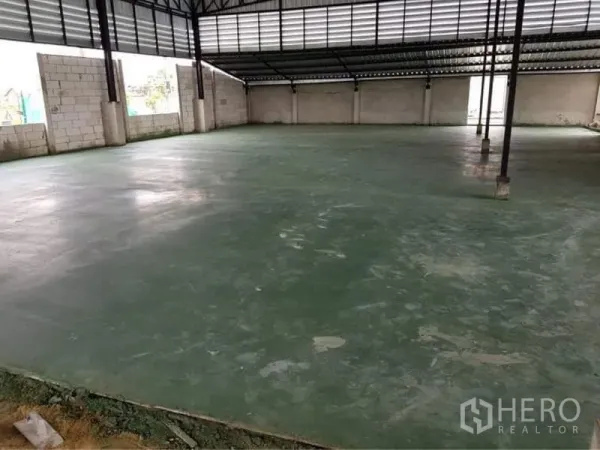 Warehouse for sale in Lam Luk Ka, Pathum Thani - Spacious warehouse interior with green epoxy concrete floor and steel truss roof.