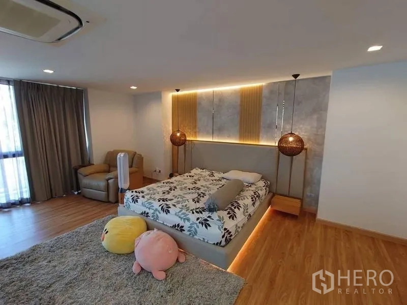联排别墅 出售在Lat Phrao, Bangkok - 主卧空间宽敞，木地板，灯带床头与休闲椅。