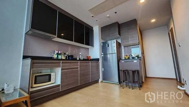 Condominium for rent in Khlong Toei, Bangkok - Modern built-in kitchen with upper cabinets, fridge and breakfast bar.