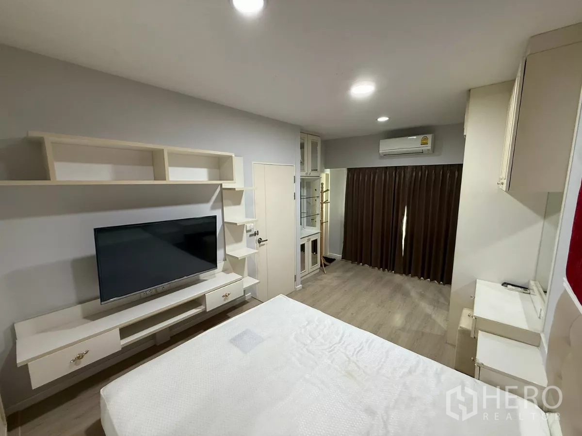 Townhouse for rent in Suan Luang, Bangkok - Bedroom with built-in TV console, shelving and blackout curtains.