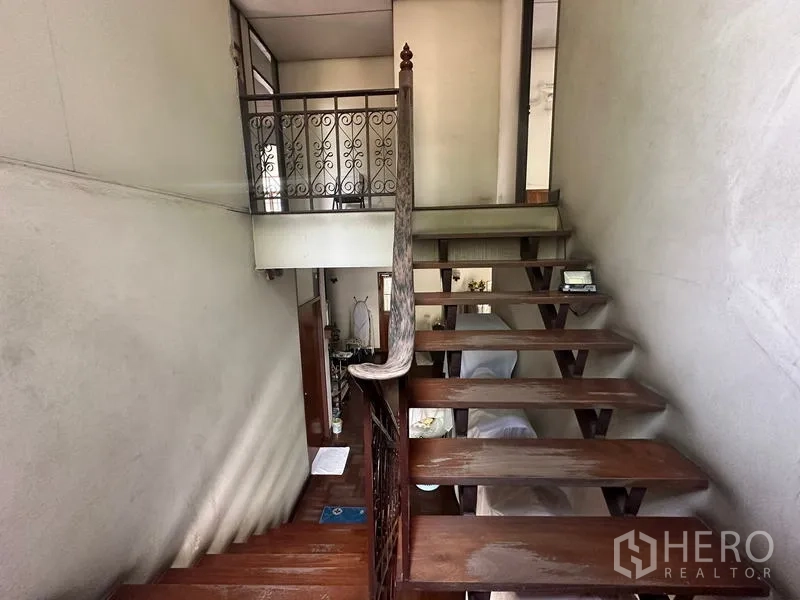 Detached House for sale in Phra Khanong, Bangkok - Open-riser wooden staircase with decorative metal railing between floors.