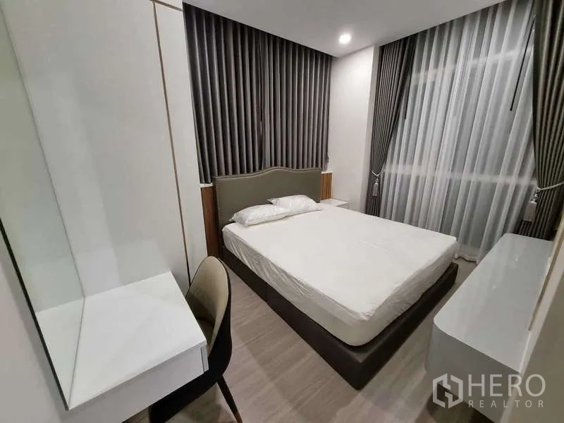 Condominium for rent - Cozy bedroom with large windows, blackout curtains and minimalist furnishings.