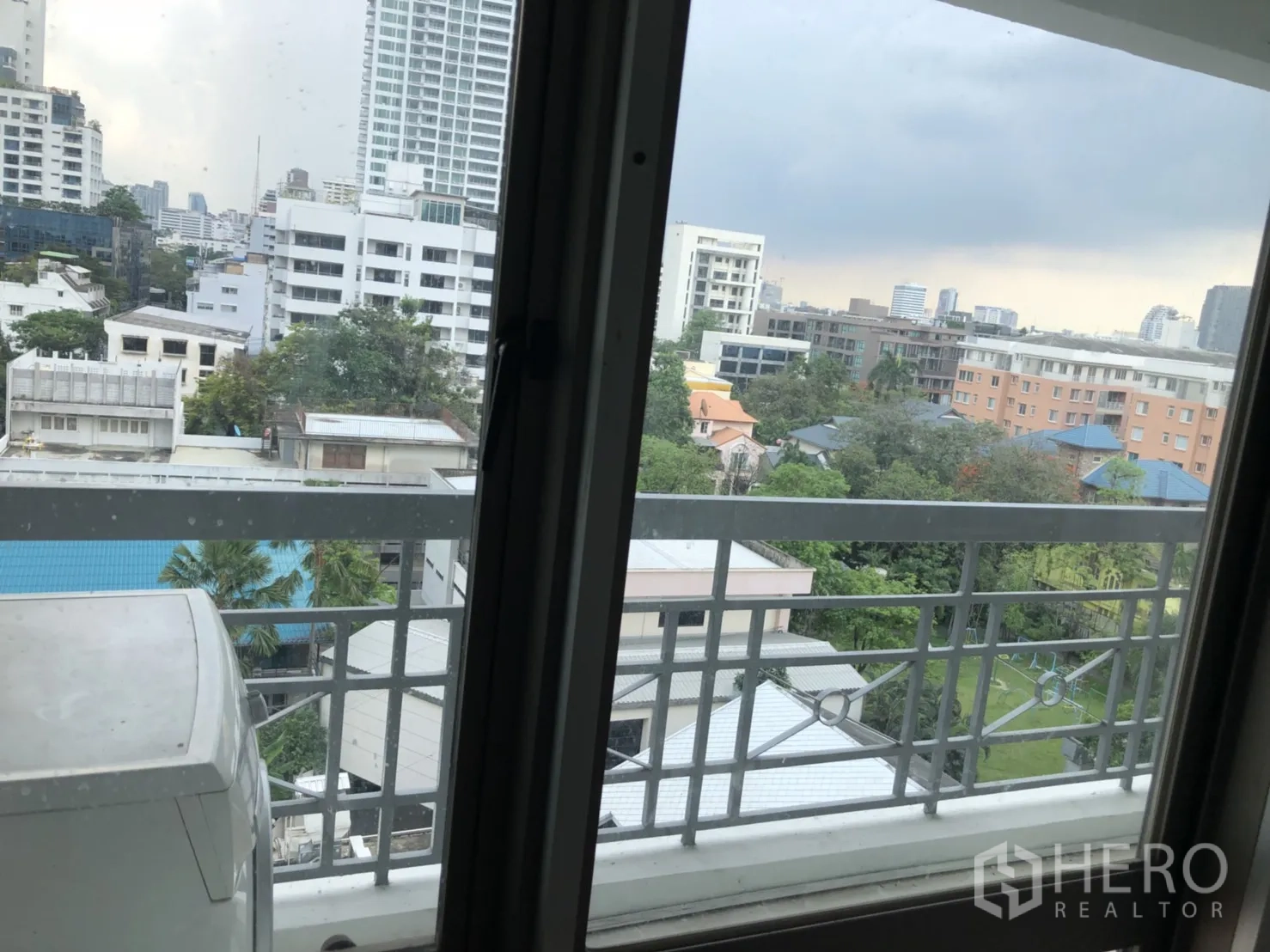 Condominium for rent in Watthana, Bangkok - Balcony view over low-rise buildings, trees and the city skyline.