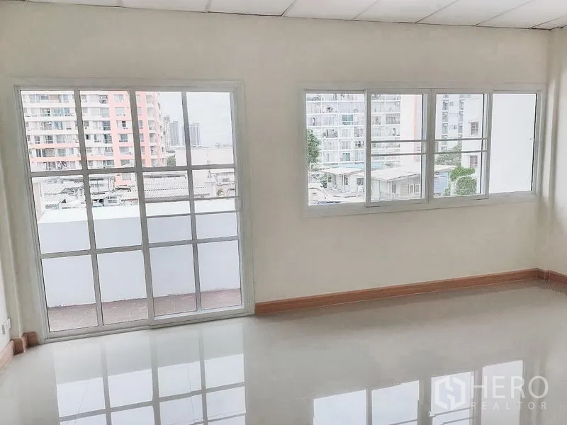 Townhouse for rent in Chatuchak, Bangkok - Bright room with large grid windows and city views from a Chatuchak townhouse.