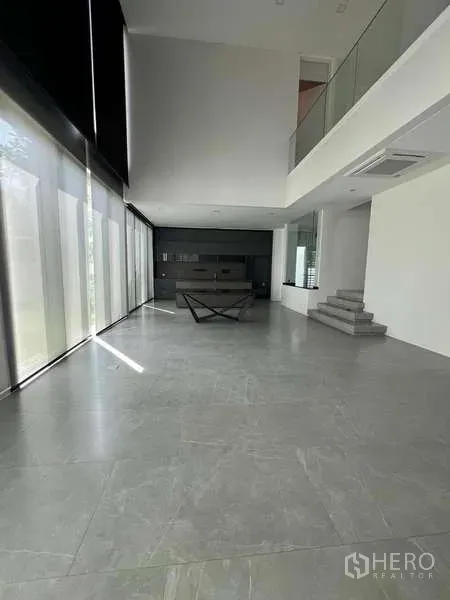 Detached House for sale in Bang Phli, Samut Prakan - Double-height living area with floor-to-ceiling windows and minimalist grey tile floors.