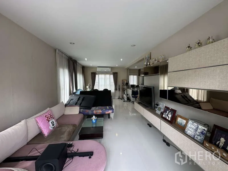 Detached House for sale in Sai Mai, Bangkok - Long living room with large windows, sofa set and built-in TV wall.