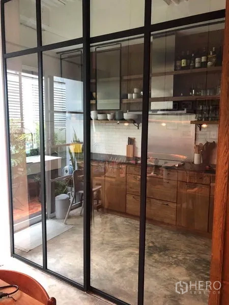 联排别墅 出售在Wang Thonglang, Bangkok - 厨房以黑框玻璃移门分隔，可望向小露台。