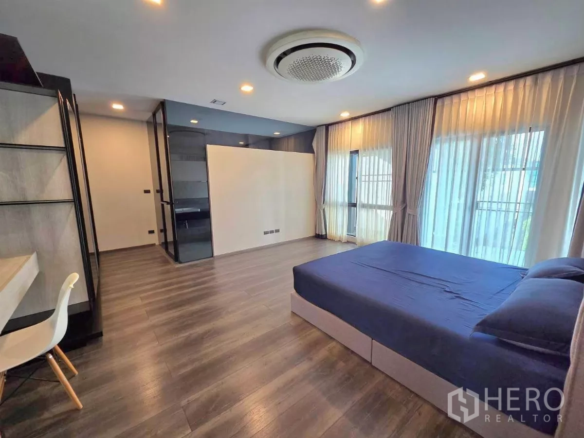 Detached House for rent in Bang Phli, Samut Prakan - Master bedroom angle showing floor-to-ceiling curtains, large windows and walk-in closet entry.