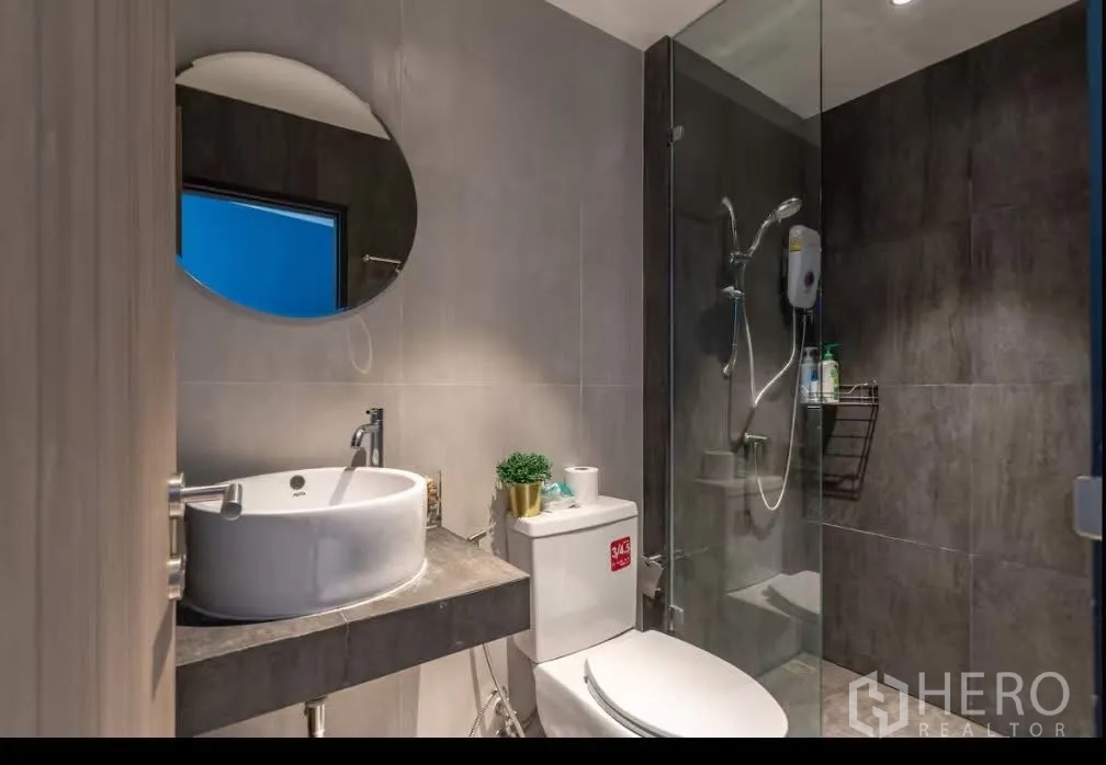联排别墅 for rent in Watthana, Bangkok - 现代卫浴，台上圆形洗手盆、坐便器与玻璃淋浴间带热水器。