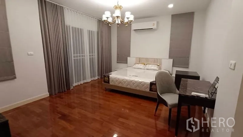独立式住宅 出租在Prawet, Bangkok - 主卧，特大床、吊灯、书桌与木地板