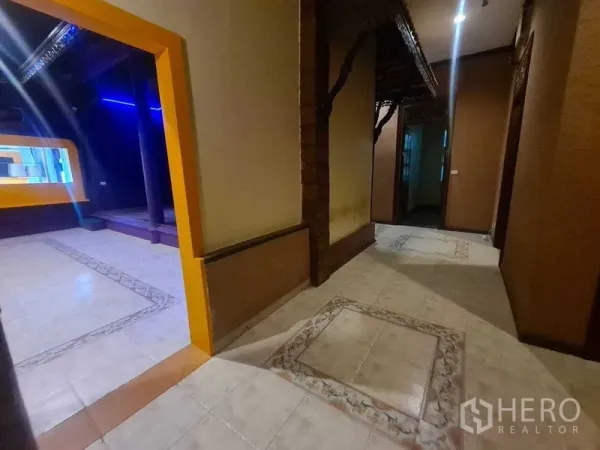 零售空间 出租在Watthana, Bangkok - 带花纹瓷砖的走廊，通向紫色零售区与抬高的展示台。