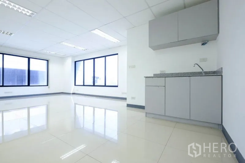 Office Space for rent in Suan Luang, Bangkok - Empty office room with wide glazed windows, tiled floors and ceiling AC unit.