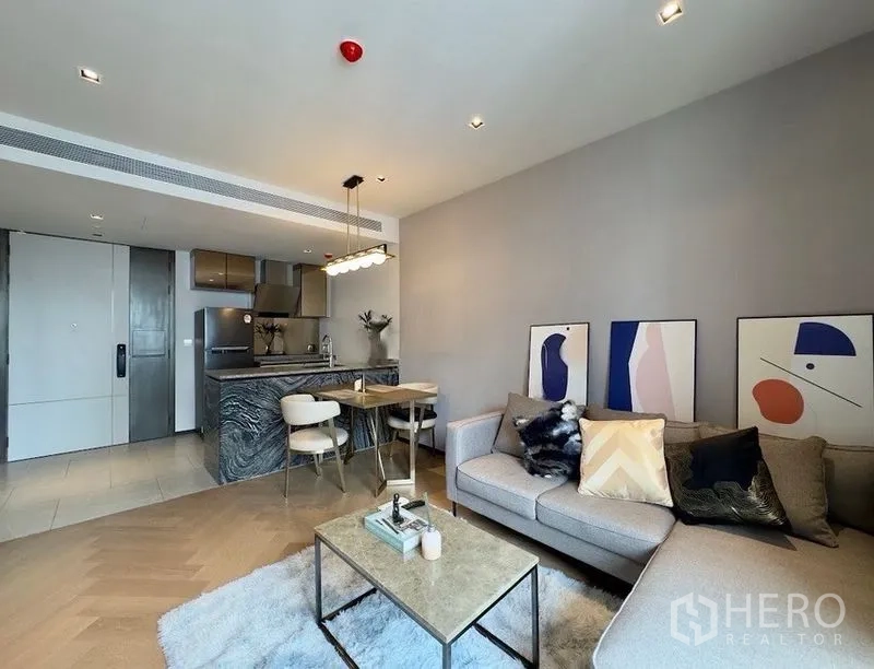 Condominium for rent or sale in Watthana, Bangkok - Open-plan lounge facing a compact kitchen and stone island with dining area.