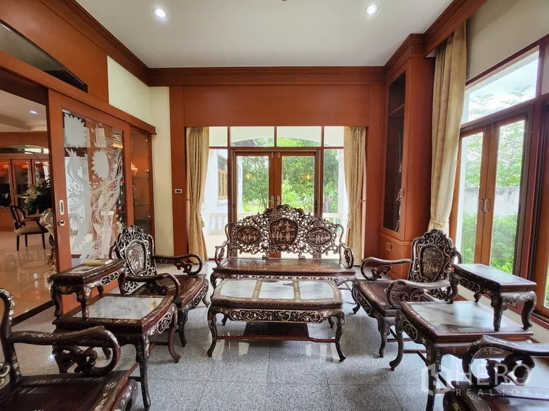 บ้าน ให้เช่าในPrawet, Bangkok - ห้องนั่งเล่นเฟอร์นิเจอร์ไม้แกะสลัก เปิดสู่สวนผ่านประตูกระจกบานเลื่อน
