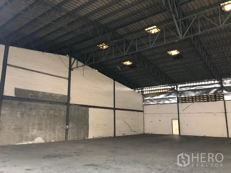 Warehouse for rent in Bang Phli, Samut Prakan - Spacious empty warehouse interior with high steel truss roof and durable concrete floor.