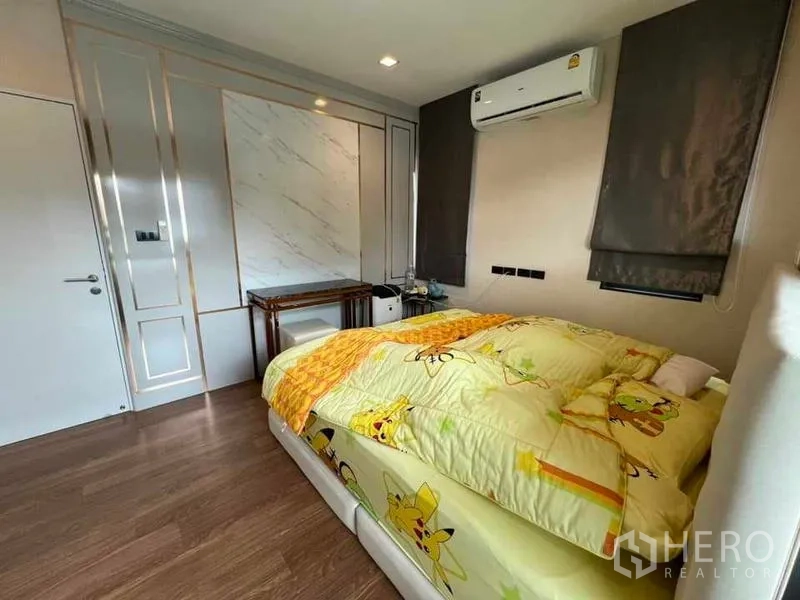 Detached House for sale in Khan Na Yao, Bangkok - Secondary bedroom with wood flooring, air-conditioning and decorative wall panels.