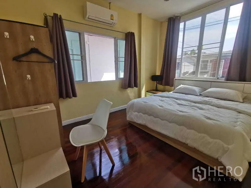 Townhouse for rent in Chatuchak, Bangkok - Air-conditioned bedroom with king bed, wardrobe and corner windows.
