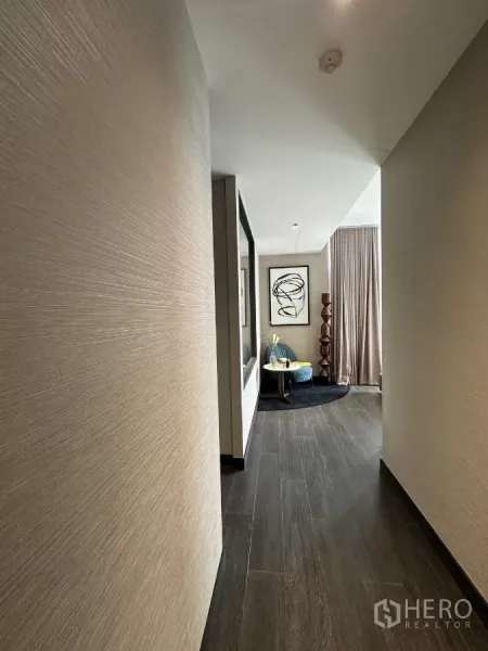 Condominium for rent in Bang Rak, Bangkok - Hallway with dark wood flooring opening to a cozy seating nook and large window.