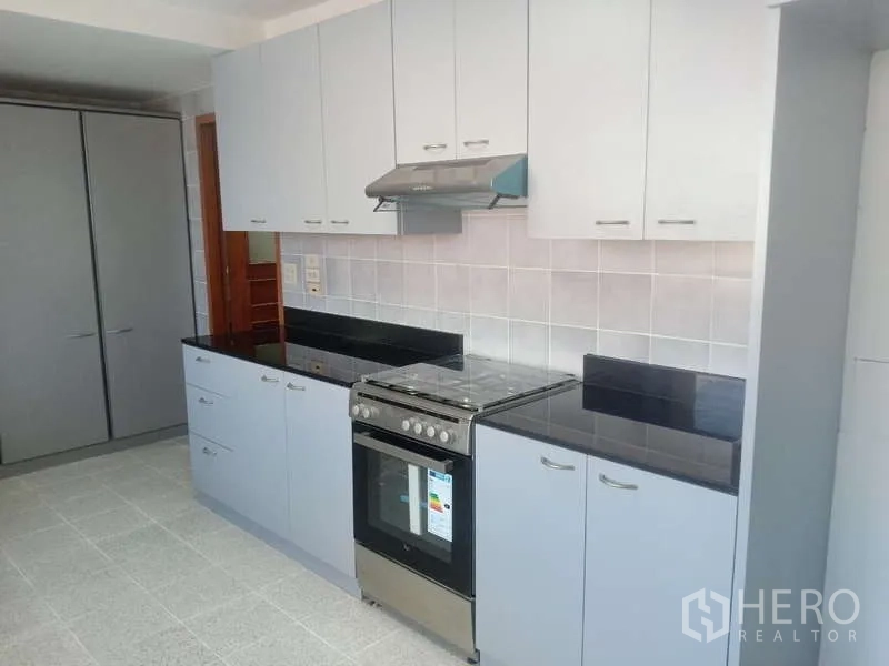 Condominium for rent in Khlong Toei, Bangkok - Separate kitchen with oven, range hood, black stone counters and ample cabinets.