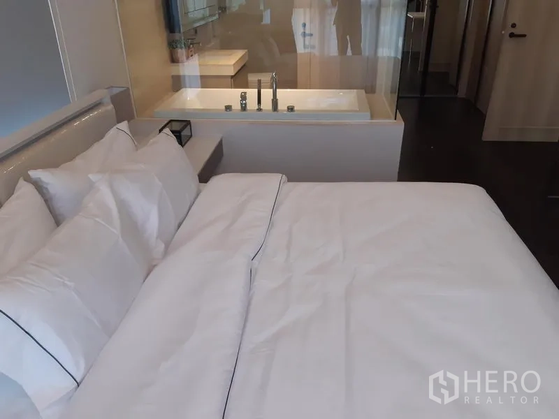 Condominium for rent in Watthana, Bangkok - Primary bedroom with bathtub behind a glass partition.