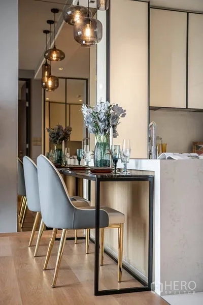 Condominium for rent in Khlong Toei, Bangkok - Compact dining nook with modern chairs and marble kitchen counter