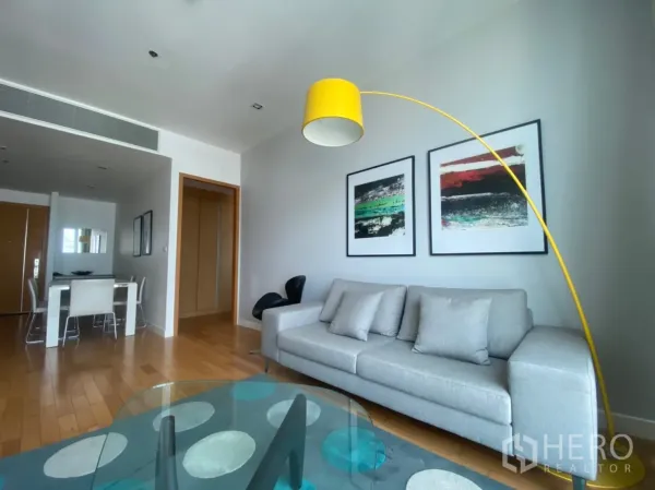 Condominium for rent or sale in Khlong Toei, Bangkok - Open-plan living and dining area with hardwood floors, contemporary sofa and four-seat dining set.