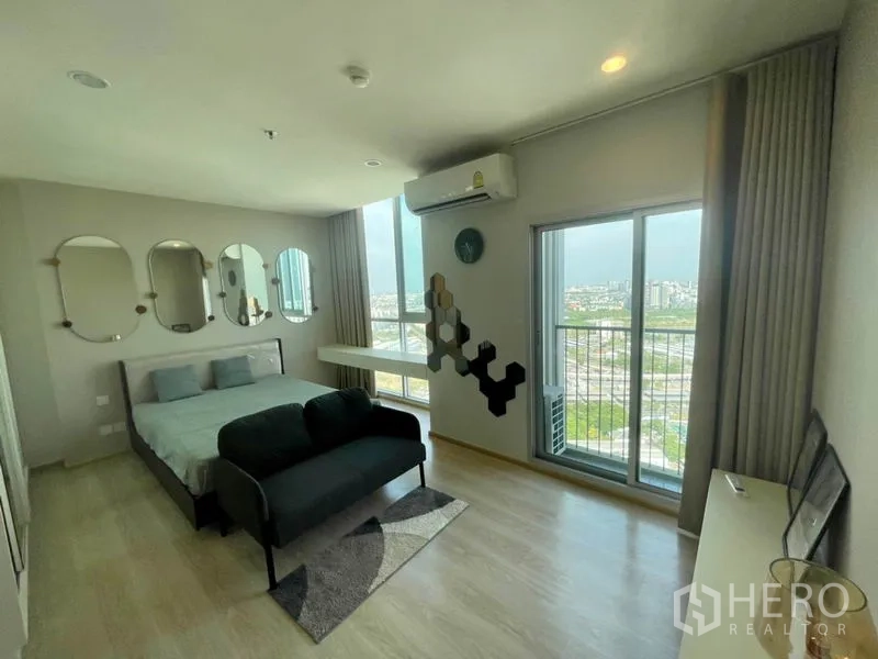 คอนโด ให้เช่าในHuai Khwang, Bangkok - ห้องนอนโปร่ง เตียง โซฟา และประตูระเบียงมองเห็นวิวกรุงเทพฯ
