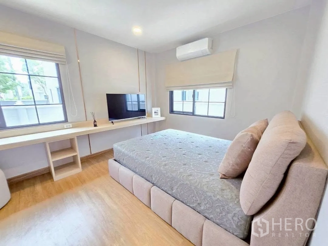 Detached House for rent in Bang Phli, Samut Prakan - Cozy bedroom with built-in study desk, two windows, and an upholstered bed.