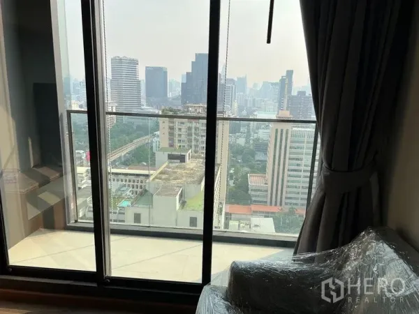 Condominium for rent in Ratchathewi, Bangkok - Living area with floor-to-ceiling sliding doors opening to Bangkok city view.