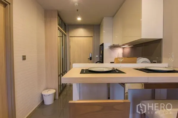 Condominium for sale in Watthana, Bangkok - Compact kitchen with breakfast bar, built-in cabinets and entryway in a modern condo.