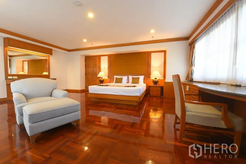 อพาร์ทเมนท์ ให้เช่าในWatthana, Bangkok - ห้องนอนมาสเตอร์กว้าง เห็นเก้าอี้อาร์มแชร์ กระจกโต๊ะเครื่องแป้ง และพื้นไม้เงางาม