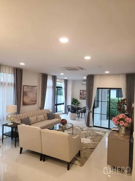 Detached House for rent in Saphan Sung, Bangkok - Open-plan living room with L-shaped sofa and glass doors to the garden.