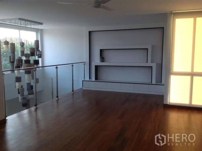 Detached House for rent in Lat Phrao, Bangkok - Upper-floor family area with wood flooring, glass railing, and built-in wall unit.